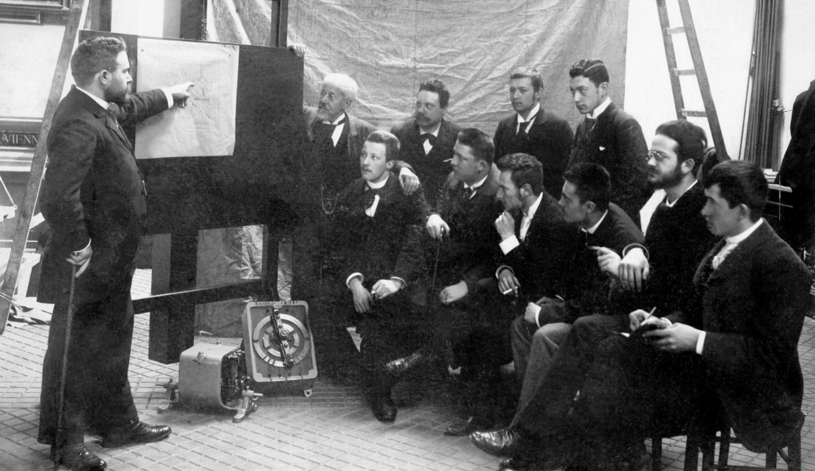 1895: Ferdinand Porsche (seated furthest to the right) at the electrical company Bela Egger & Co., later Vereinigte Elektrizitäts AG, in the Favoriten district of Vienna, during a discussion between the plant manager Wessel and the engineers.
