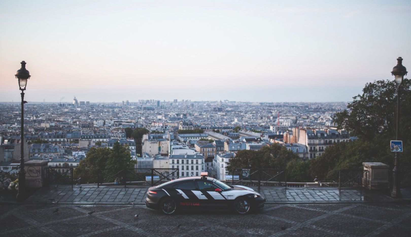 At sunrise, the journey continues. The Porsche Taycan drives through the narrow lanes of Montmartre up to the Basilica of Sacré-Cœur and a magnificent view of Paris awakening.