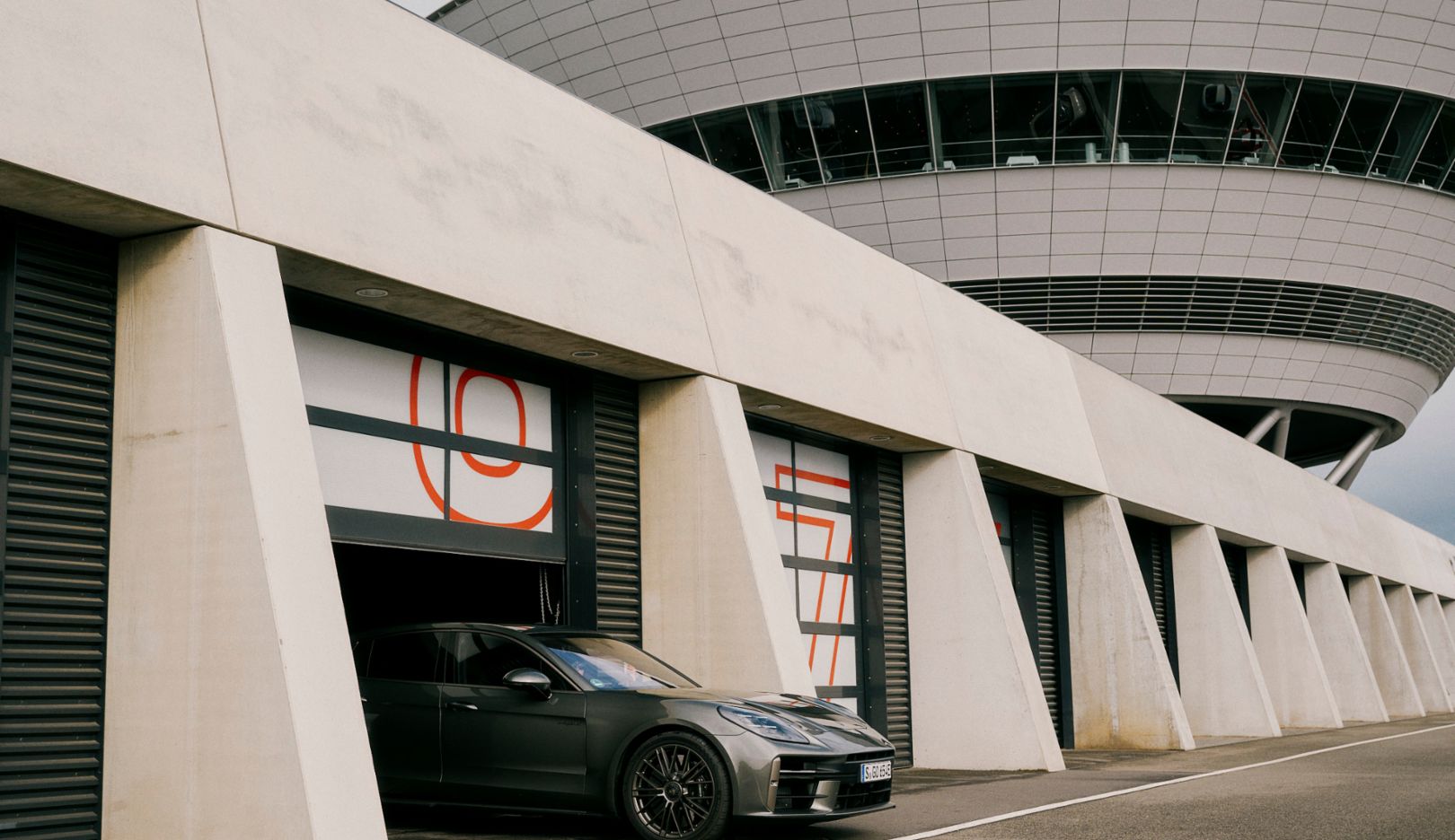 莱比锡赛道边的车库驶出了 Panamera Turbo E-Hybrid。它即将展开一段回顾之旅，探索保时捷品牌的过去。