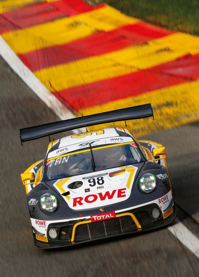 Ein Rennwagen mit der Nummer 98 fährt auf einer Strecke mit farbigen Randmarkierungen und einer dynamischen Kurve.
