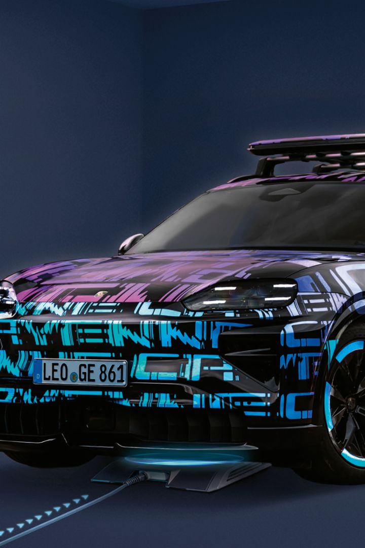 A Porsche Macan drives on a racetrack with a striking observation tower in the background and a “1,000,000” badge on the front of the vehicle.