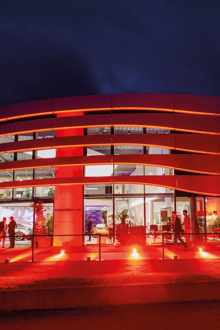 Interior shot of a Porsche 924 car with a Christophorus magazine on the passenger seat. The seats are covered in a yellow-black checkered pattern and a gear shift knob is visible.