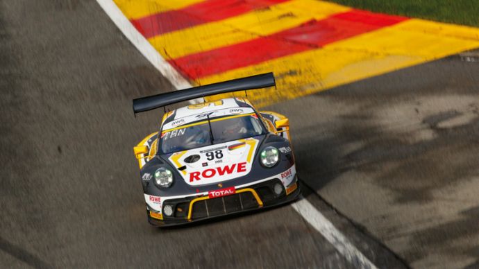 A race car with the number 98 drives on a track with colored edge markings and a dynamic curve.