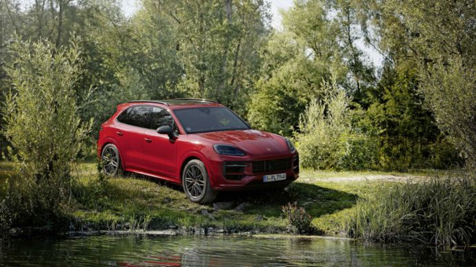 Ein roter Geländewagen steht am Ufer eines kleinen Sees. 
