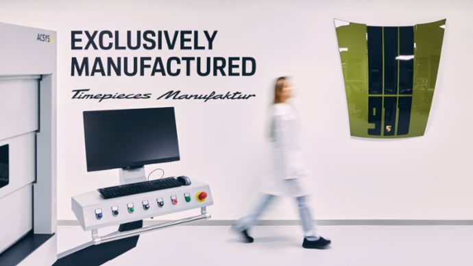 Eine Frau in einem weißen Laborkittel geht in einer modernen Uhrmanufaktur an einem Monitor und einem Gerät vorbei, das in einem eleganten Raum steht.