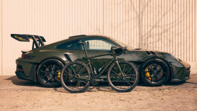 A sports car and a bike stand side by side.